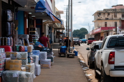 Vista ilustrativa de área comercial de fronteira em Guajará-Mirim, com mercadorias e circulação urbana, sem textos legíveis
