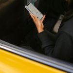 Passageira observa um aplicativo de mapas no celular enquanto viaja em um veículo de transporte.