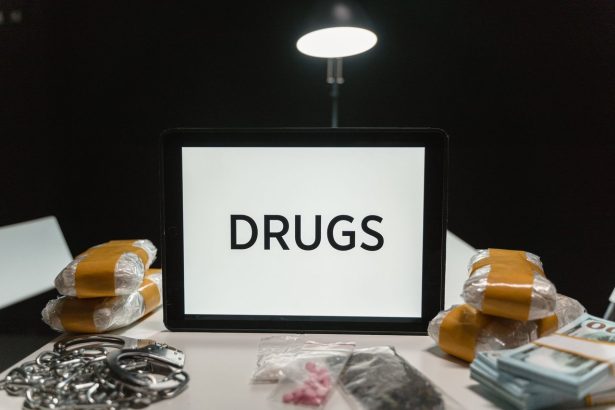 Drogas, dinheiro e algemas dispostos sobre uma mesa sob iluminação intensa.