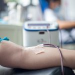 Braço de uma pessoa durante procedimento de doação de sangue em ambiente médico