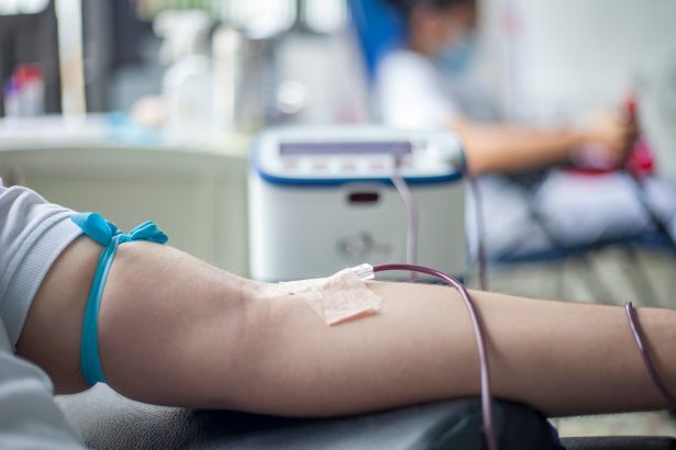 Braço de uma pessoa durante procedimento de doação de sangue em ambiente médico